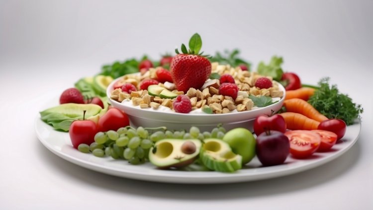 Plate of fresh fruits, vegetables, and granola with strawberries, avocados, tomatoes, carrots, greens, and grapes arranged on a white background.