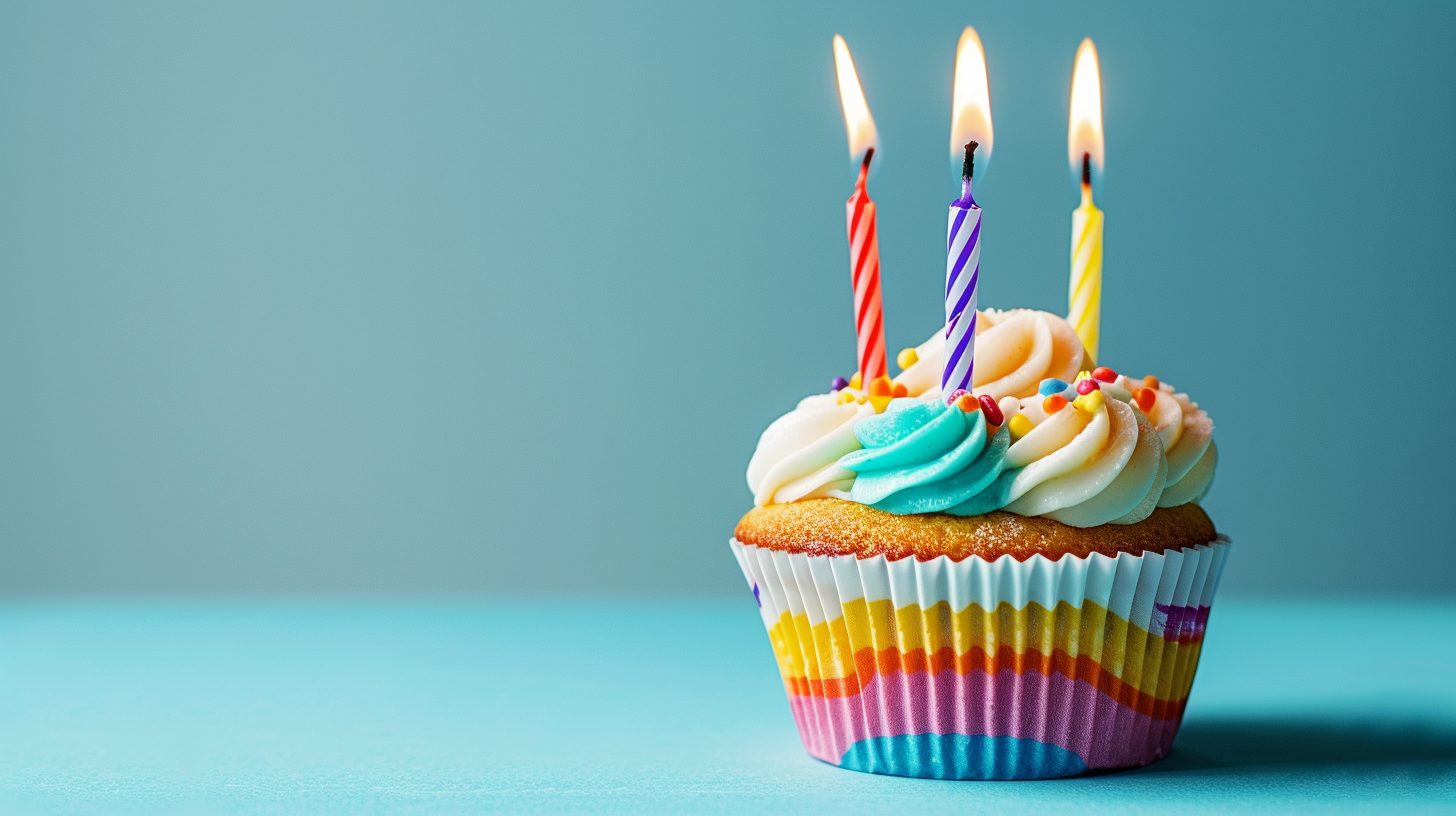 Cupcake with colorful candles on a blue background, representing birthday joy and celebration.