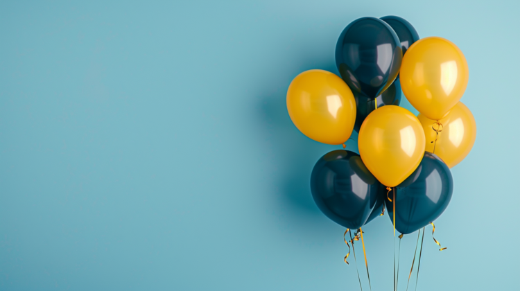 Dark blue and yellow balloons on a light blue background with copy space for celebrations.