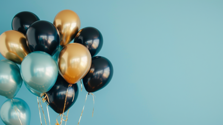 Black, gold, and teal balloons on a light blue background with copy space on the right side.