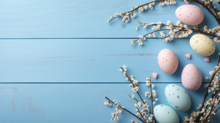 Pastel Easter eggs and willow branches on a blue wooden table with copy space.