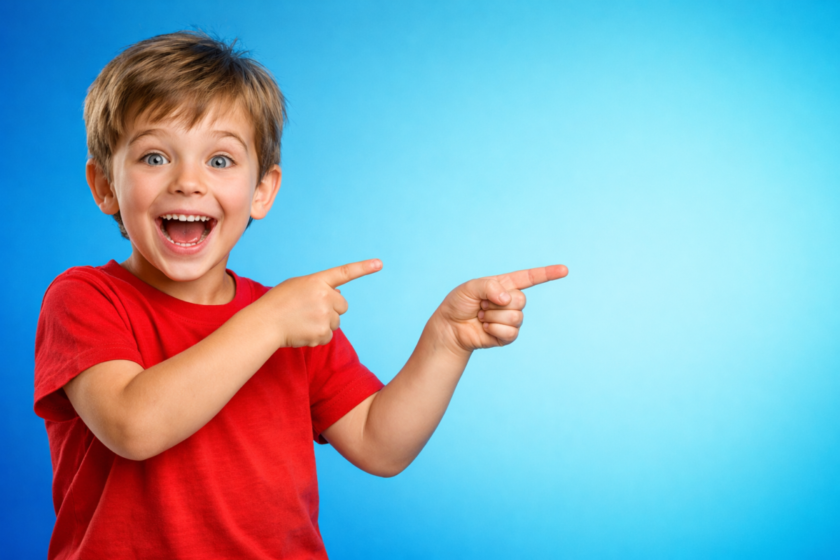 Happy young boy in red shirt enthusiastically pointing to the right on blue gradient background