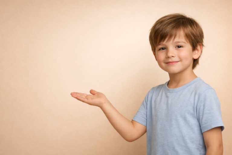 Smiling young boy in a light blue t-shirt showing his open palm to the side against a plain beige background