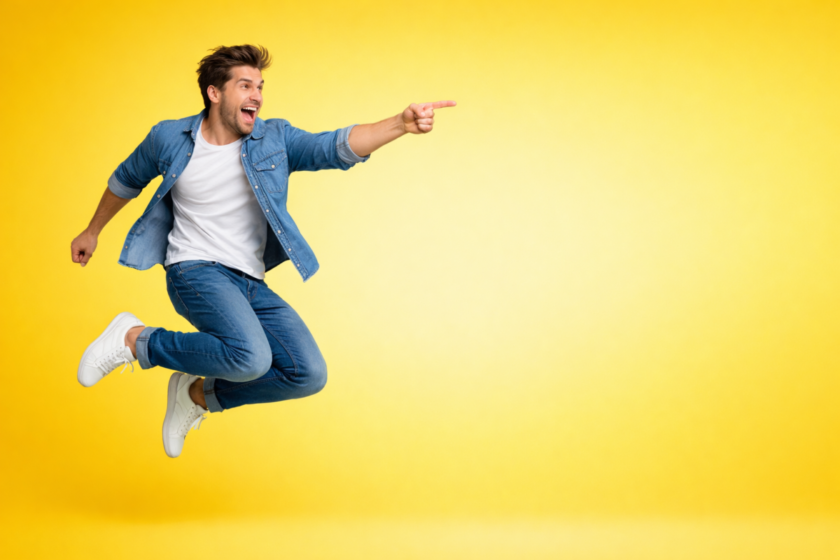 Happy young man in denim outfit captured mid-jump against a bright yellow backdrop symbolizing Easter cheer and vibrant spring energy