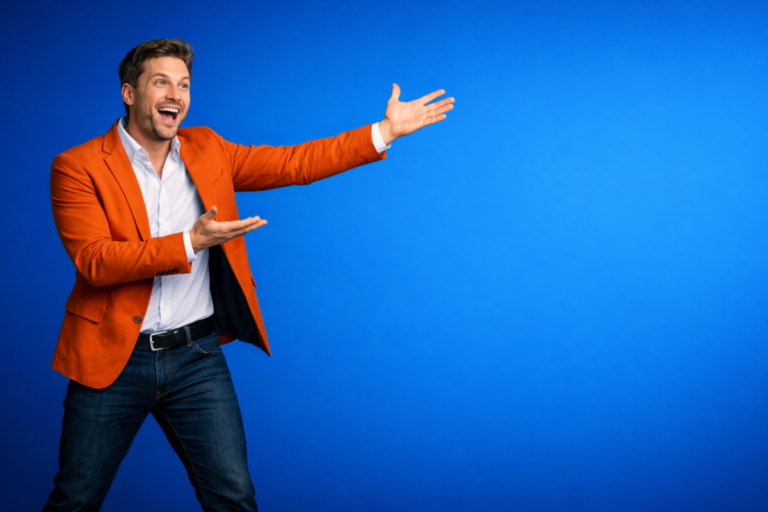 Happy man wearing an orange blazer and white shirt enthusiastically gesturing towards empty blue space, inviting attention