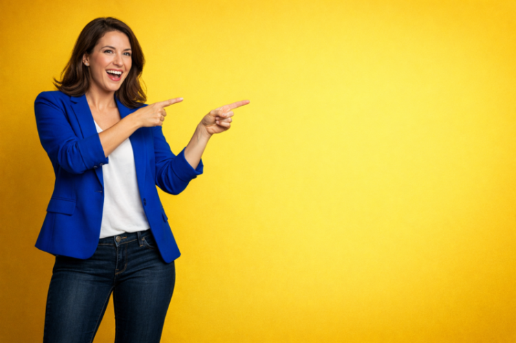 Happy woman wearing a blue blazer and jeans smiling and pointing to her right against a solid yellow background