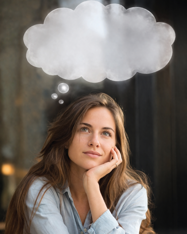 Young woman with long brown hair resting chin on hand looking upward thoughtfully with a cloudy thought bubble above