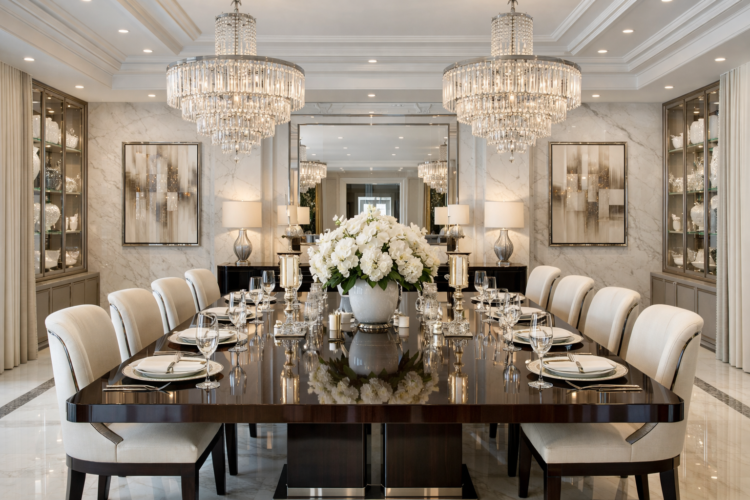 Luxurious dining room featuring a glossy dark wood table set for twelve with crystal chandeliers and white floral centerpiece